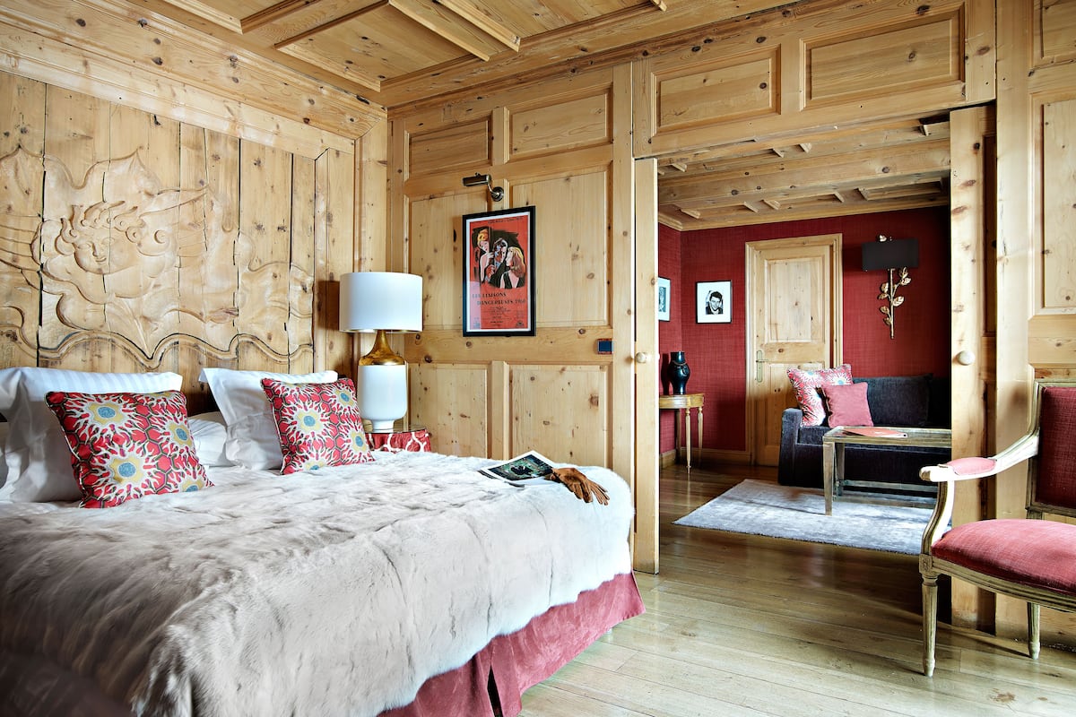 A wooden-paneled room with a bed, a chair, and a small table.