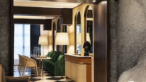 Un hall de hotel con suelo a cuadros, un sofá, una mesa y un mostrador de recepción.
