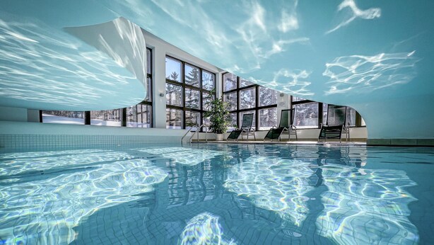 An indoor swimming pool with clear water, large windows, and a modern building structure. - Cresta Palace (Celerina-Schlarigna)