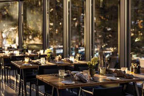 A restaurant with multiple tables set for dining, large windows, and a view of the outdoors. - Cresta Palace (Celerina-Schlarigna)