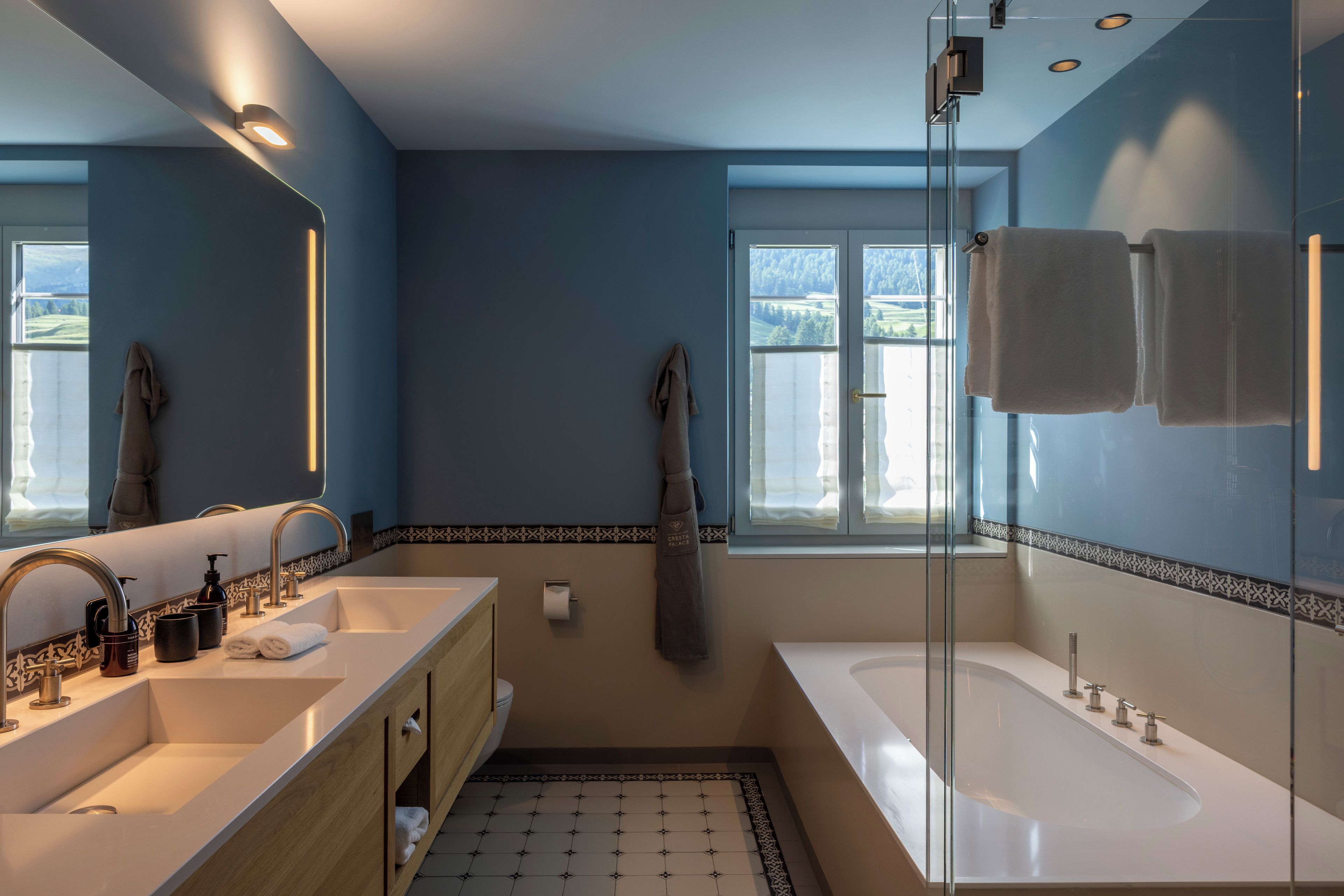 Un baño moderno con tocador doble lavabo, una bañera grande y un cerramiento de ducha de vidrio.
