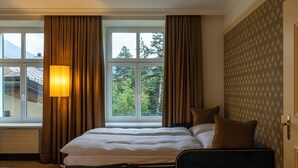 A hotel room with a bed, a window with curtains, and a view of trees. - Cresta Palace (Celerina-Schlarigna)