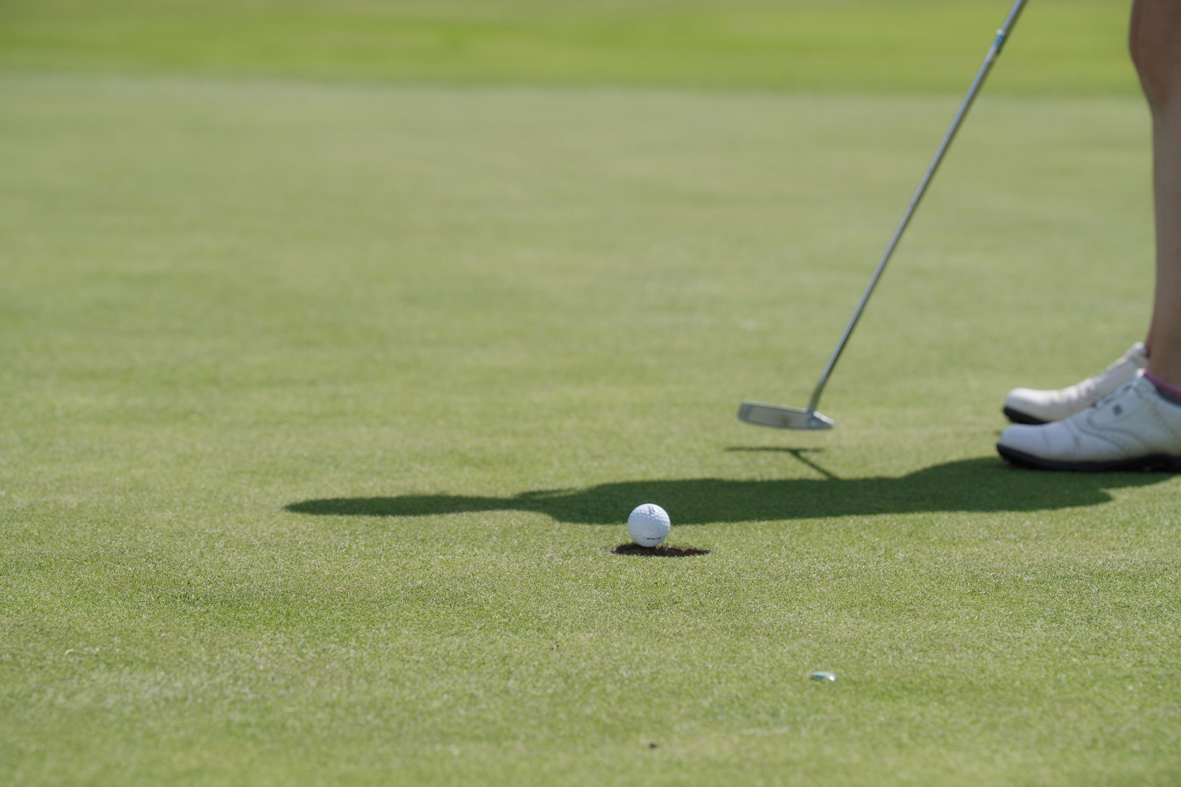 Una pelota de golf en el suelo con un palo de golf cerca.