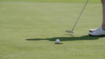 Una pelota de golf en el suelo con un palo de golf cerca.
