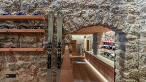 A ski shop with wooden shelves and skis, a stone wall, and a wooden floor. - Cresta Palace (Celerina-Schlarigna)