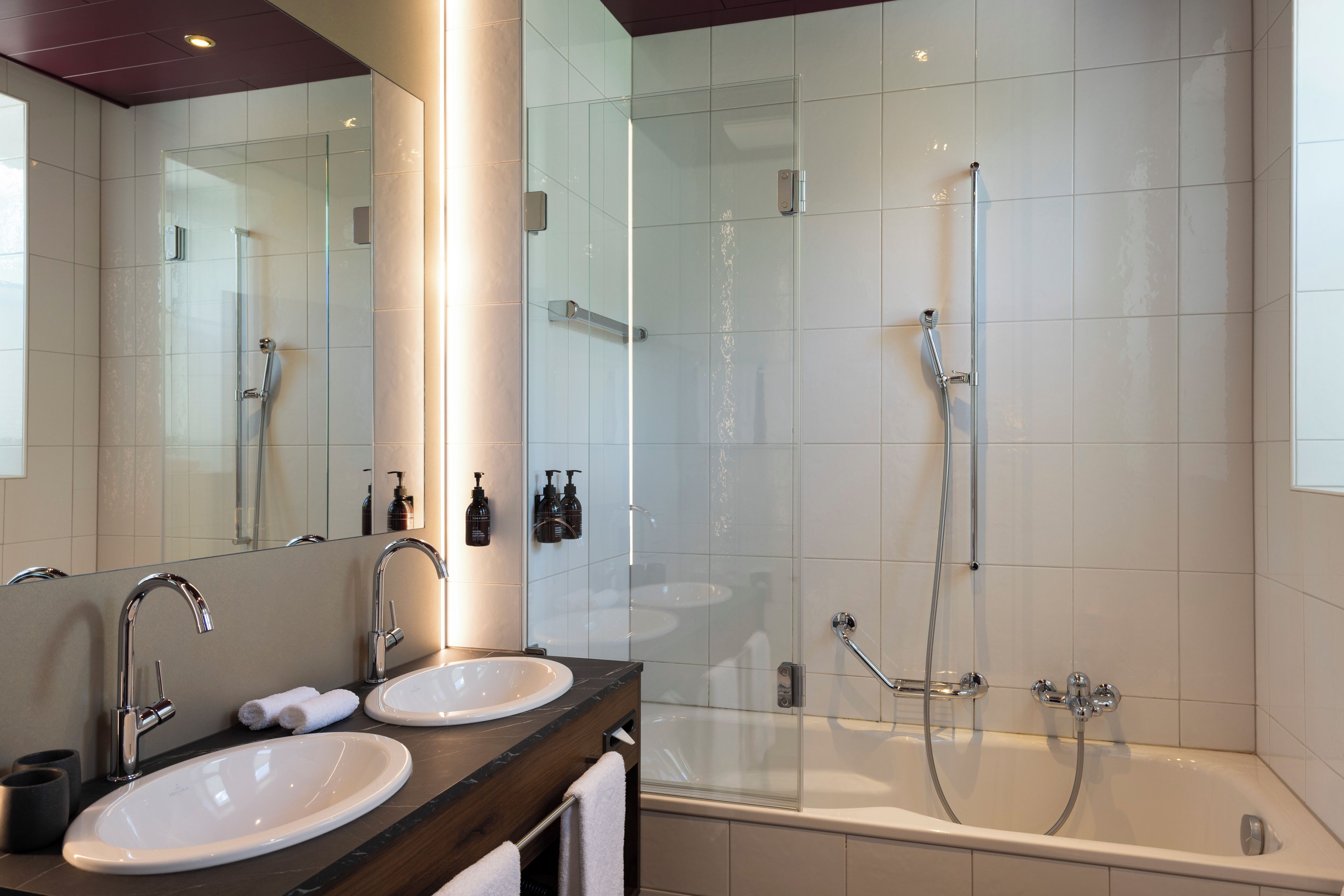 Un baño moderno con dos lavamanos, un espejo grande y una ducha a ras de suelo.
