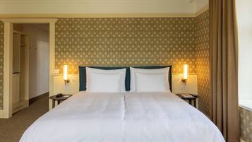 Ein Hotelzimmer mit einem großen Bett, zwei Nachttischen und einer Tür zu einem weiteren Raum.