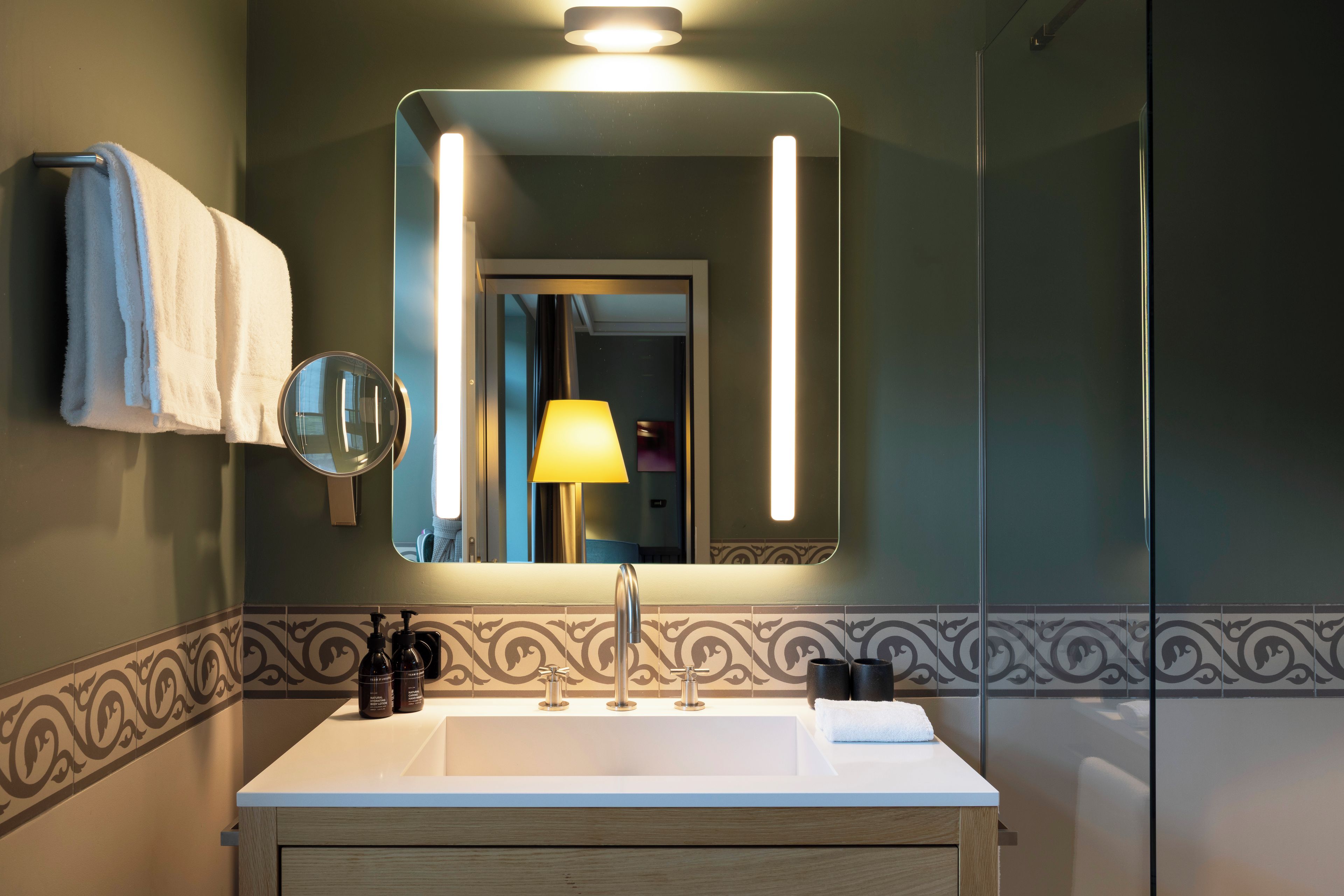 A bathroom with a white sink, a mirror, a towel, and a bottle of lotion.