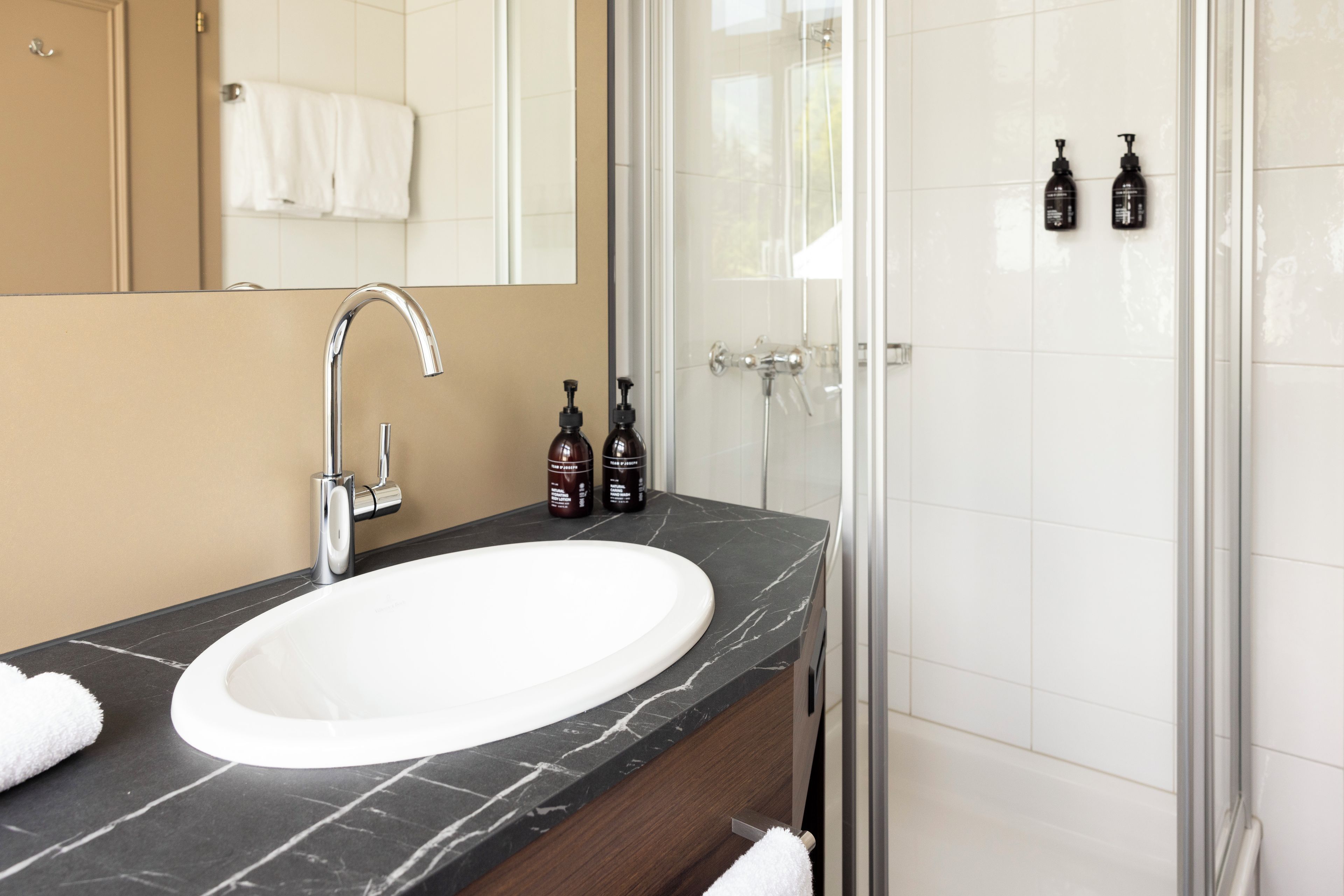 A bathroom with a white sink, a mirror, and a shower area.