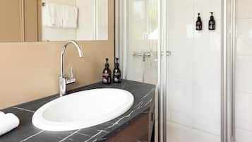 A bathroom with a white sink, a mirror, and a shower area.