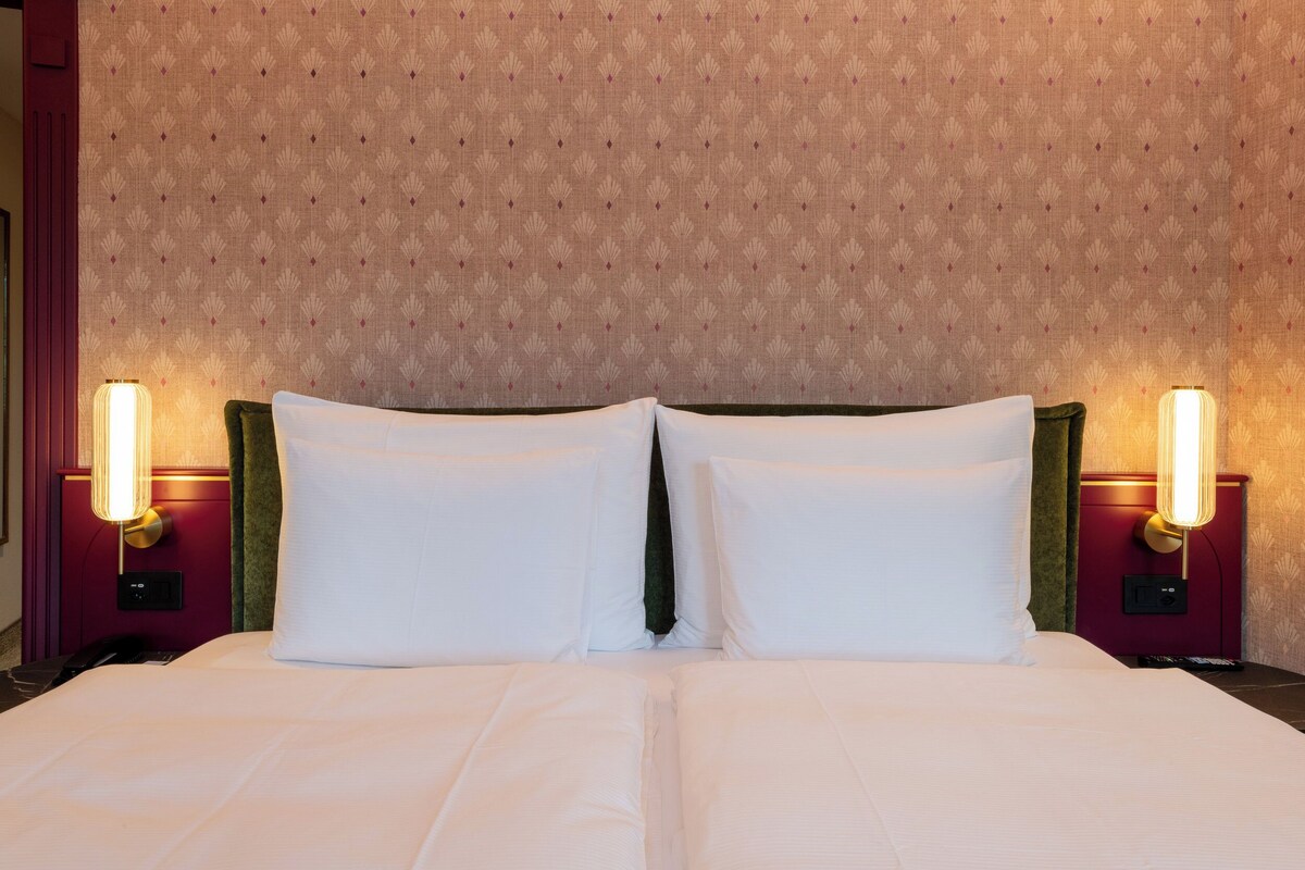 Ein Hotelzimmer mit einem großen Bett, zwei Nachttischlampen und einer Wand mit Muster.