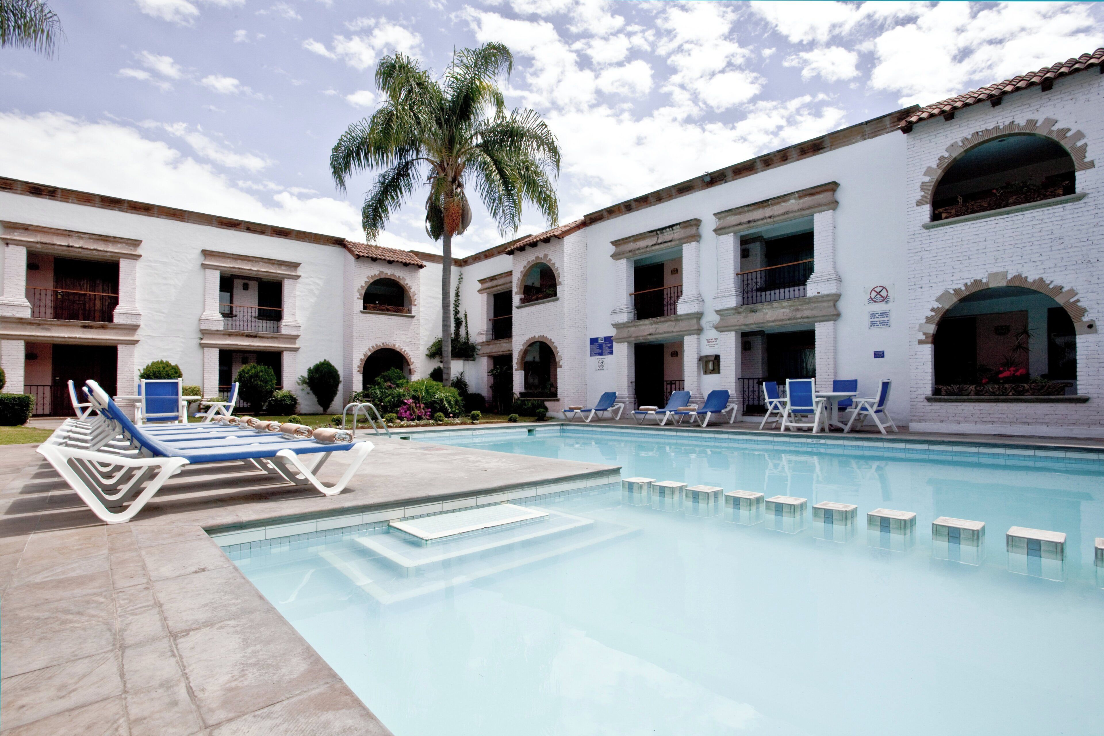A pool area with lounge chairs and a palm tree.