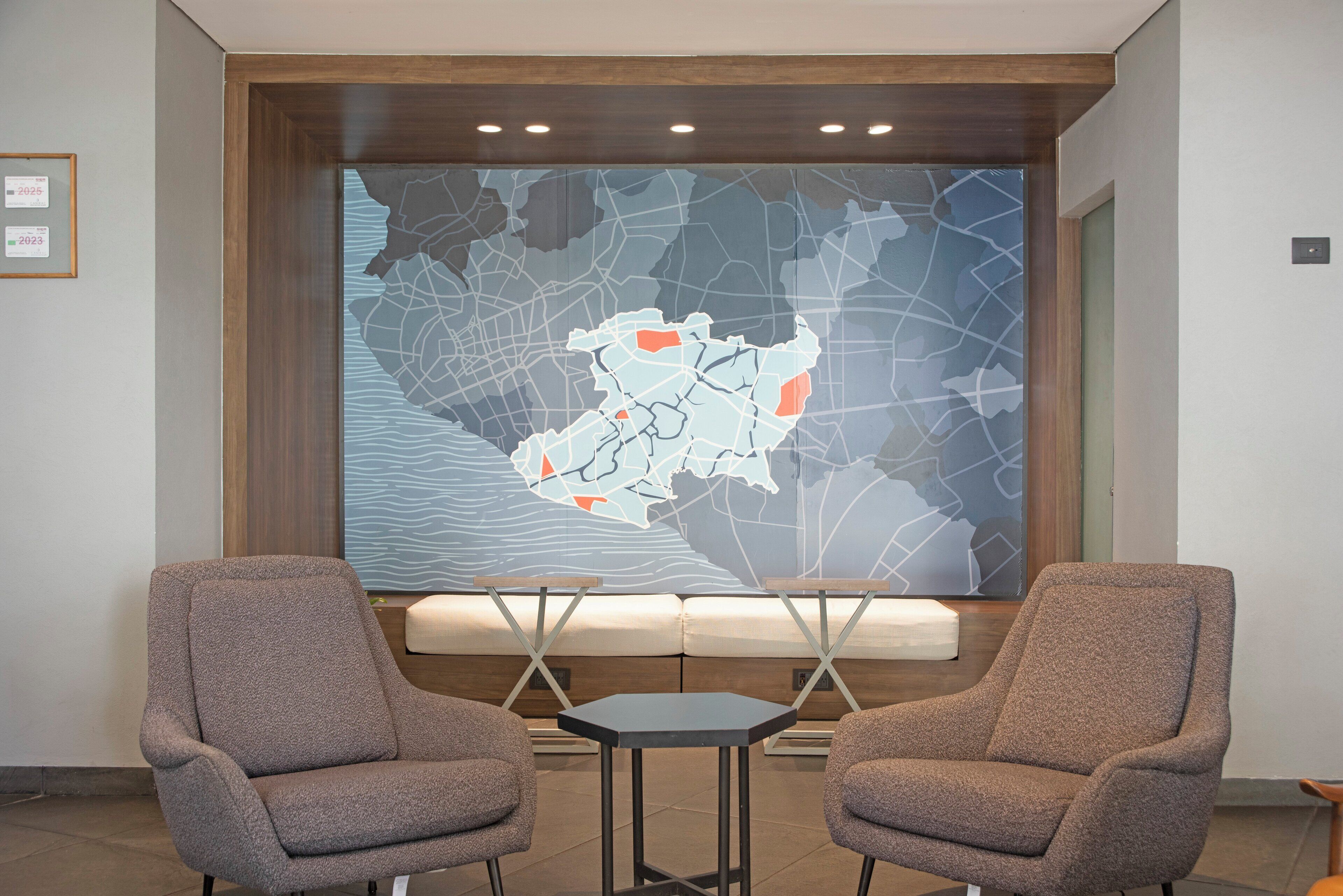 A lobby with two armchairs, a small table, and a large wall map.