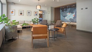 Un moderno vestíbulo de hotel con un sofá, sillas, una mesa de centro y un mapa grande en la pared.