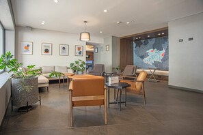 Un moderno vestíbulo de hotel con un sofá, sillas, una mesa de centro y un mapa grande en la pared.