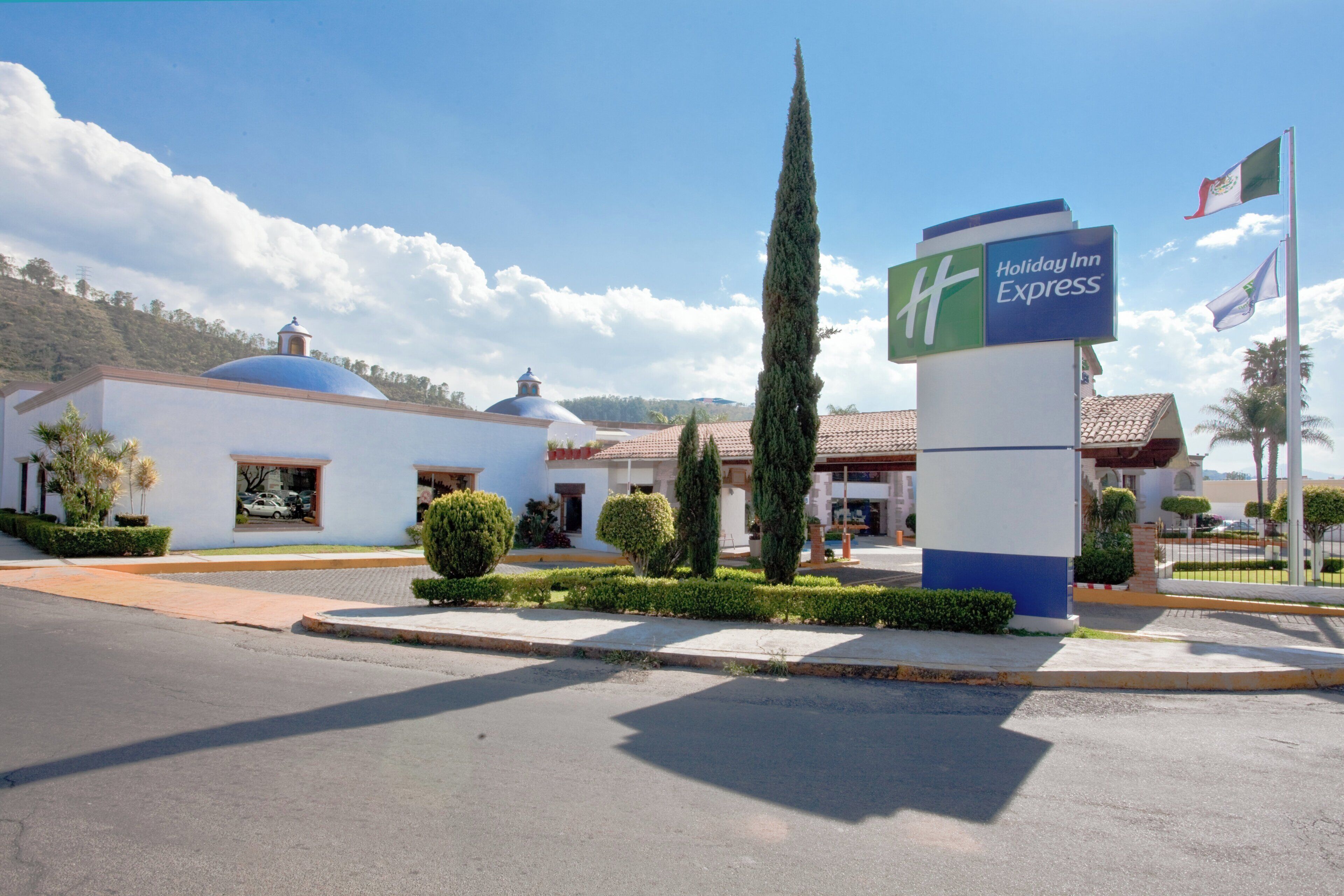A Holiday Inn Express hotel with a clear sky, a flag, and a well-maintained garden.