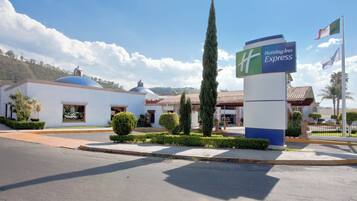 A Holiday Inn Express hotel with a clear sky, a flag, and a well-maintained garden.