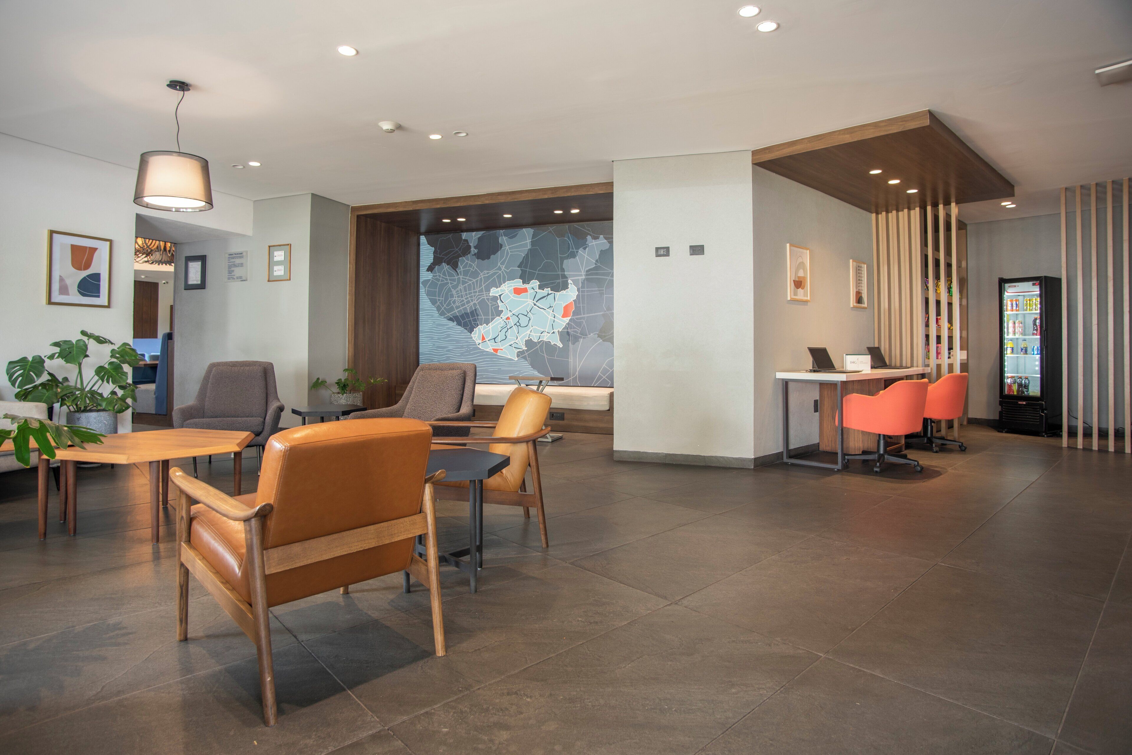 A modern hotel lobby with a large map on the wall, comfortable seating, and a reception desk.