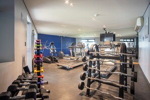 A gym with various exercise equipment, including dumbbells, treadmills, and weight machines.