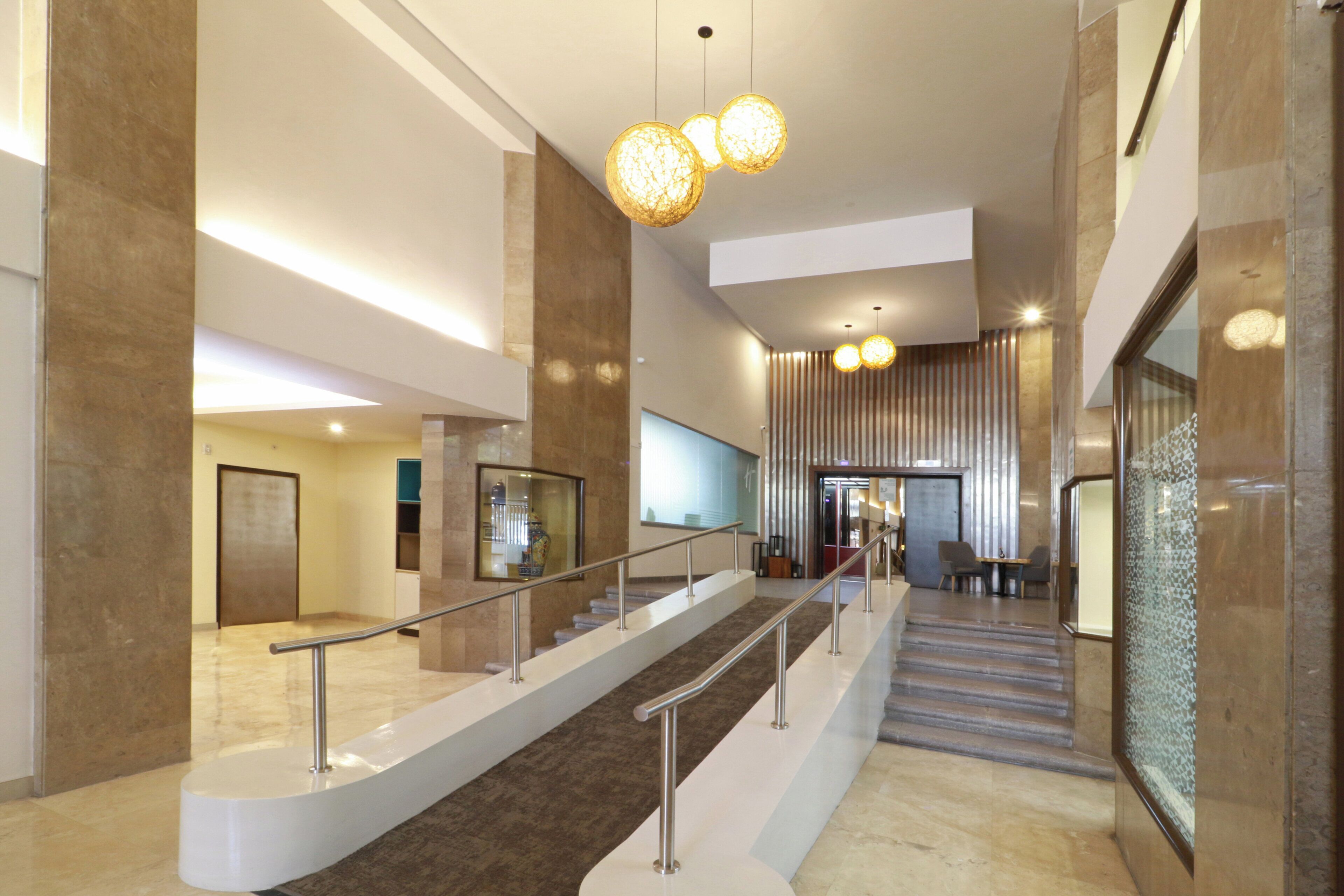 Un interior modern amb una escala, baranes metàl·liques i lluminàries esfèriques penjants.