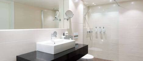 A modern bathroom with a large mirror, a white sink, and a shower area.