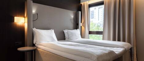 Una habitación de hotel moderna con una cama grande, una mesita de noche y vistas a la ciudad a través de la ventana.