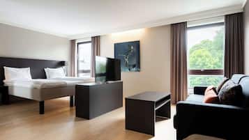 Ein modernes Hotelzimmer mit Bett, Fernseher, Sofa und einem Fenster mit Vorhängen.