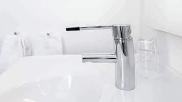 A modern bathroom with a chrome faucet, a white sink, and a clear glass on the counter.