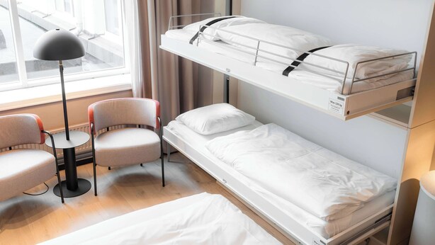 A bunk bed with a desk and chairs, a window with curtains, and a lamp. - Scandic Oslo City (Oslo)