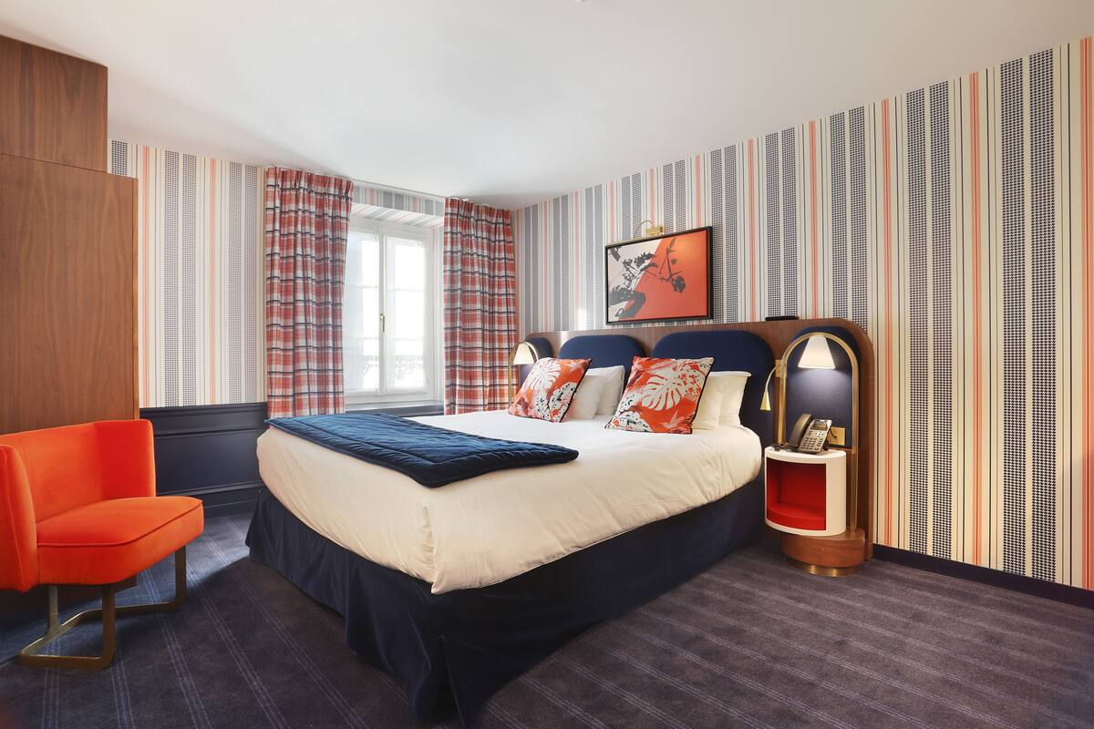 A modern hotel room with a large bed, a desk, and a chair.