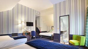 Een hotelkamer met twee bedden, een bureau, een stoel en een badkamer zichtbaar door een open deur.