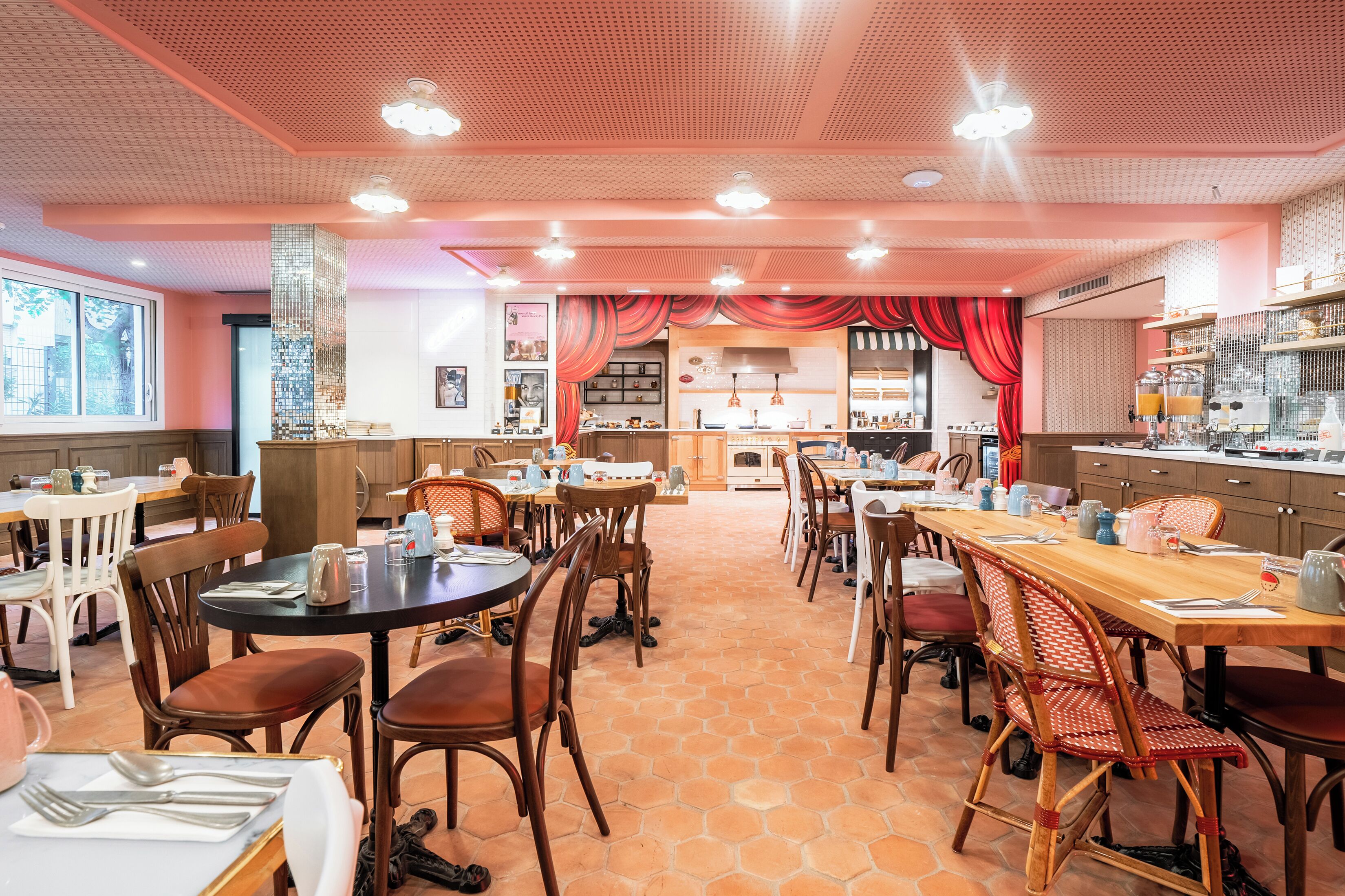 Un restaurante con varias mesas y sillas, una zona de cocina y un ventanal grande.