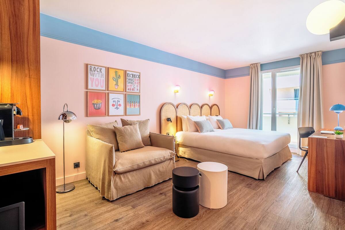 A hotel room with a bed, a sofa, a desk, and a lamp.