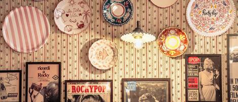 Una pared con varios elementos enmarcados, incluyendo un cartel con la palabra 'ROCKYPOP' y una fotografía enmarcada.