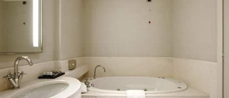 Un baño con lavamanos, espejo y bañera.