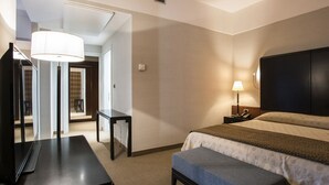 Una habitación de hotel con cama, mesita de noche, lámpara y un espejo grande.