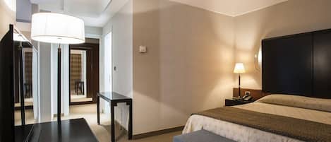 Una habitación de hotel con cama, mesita de noche, lámpara y un espejo grande.