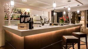 Un área de bar con una barra larga, botellas de licores y plantas decorativas.