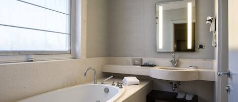 A modern bathroom with a large bathtub, two sinks, a vanity, and a mirror.