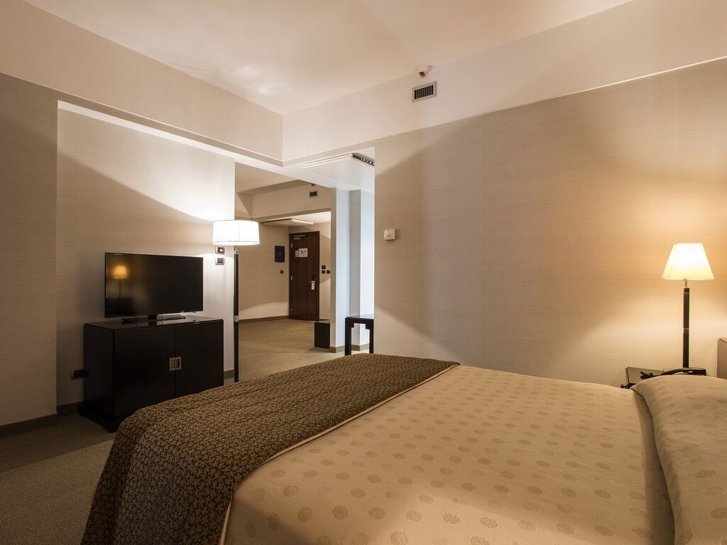 Habitación de hotel con cama, televisión, escritorio y lámpara.