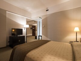 Una camera d'albergo con un letto, una televisione, una scrivania e una lampada.