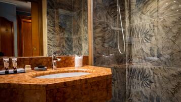 A modern bathroom with a marble sink, a glass-enclosed shower, and a bathtub.
