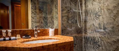 A modern bathroom with a marble sink, a glass-enclosed shower, and a bathtub.