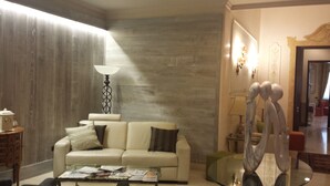 A living room with a sofa, a coffee table with magazines, a lamp, and a decorative sculpture. - Hotel Palazzo Lovera (Cuneo)