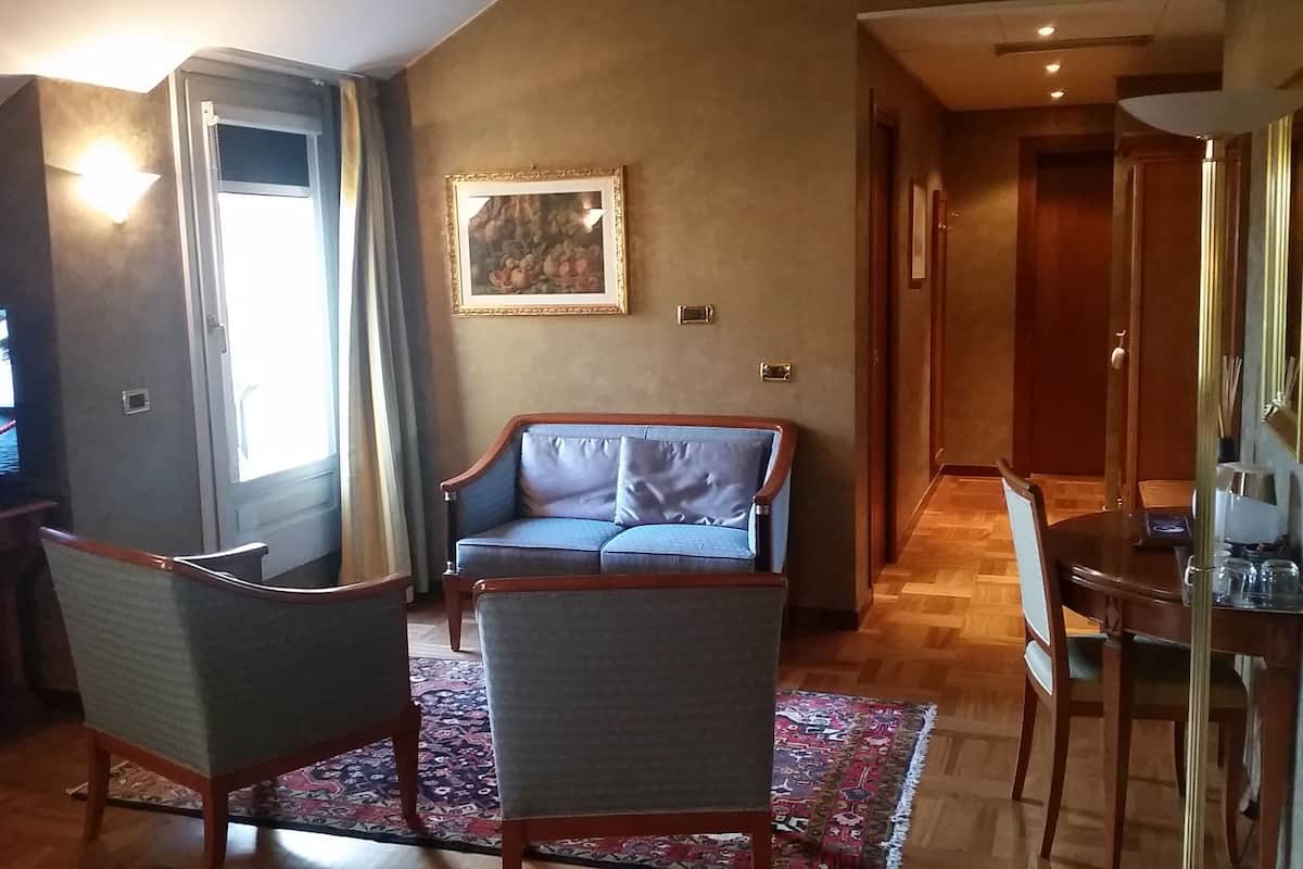 A living room with a television, a sofa, a dining table, and a patterned rug.
