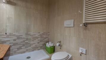 A modern bathroom with a bathtub, toilet, and a green basket of toiletries.