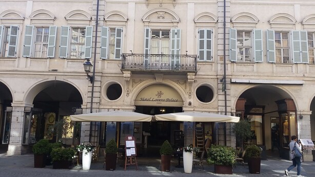 A historic building with a central entrance, arched doorways, and a balcony with railings. - Hotel Palazzo Lovera (Cuneo)