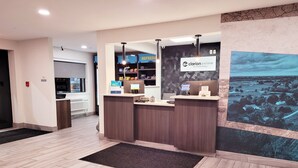 Un comptoir d’accueil avec une enseigne « Clarion Pointe by Choice Hotels », un écran numérique et une pancarte « Bienvenue ».