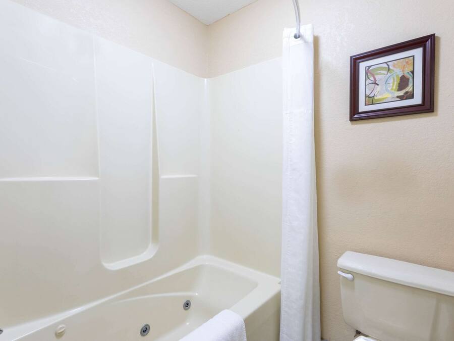 A bathroom with a bathtub, toilet, and a framed picture on the wall.