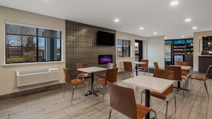 Un restaurant moderne avec des tables et des chaises, un téléviseur à écran plat fixé au mur et un distributeur automatique en arrière-plan.